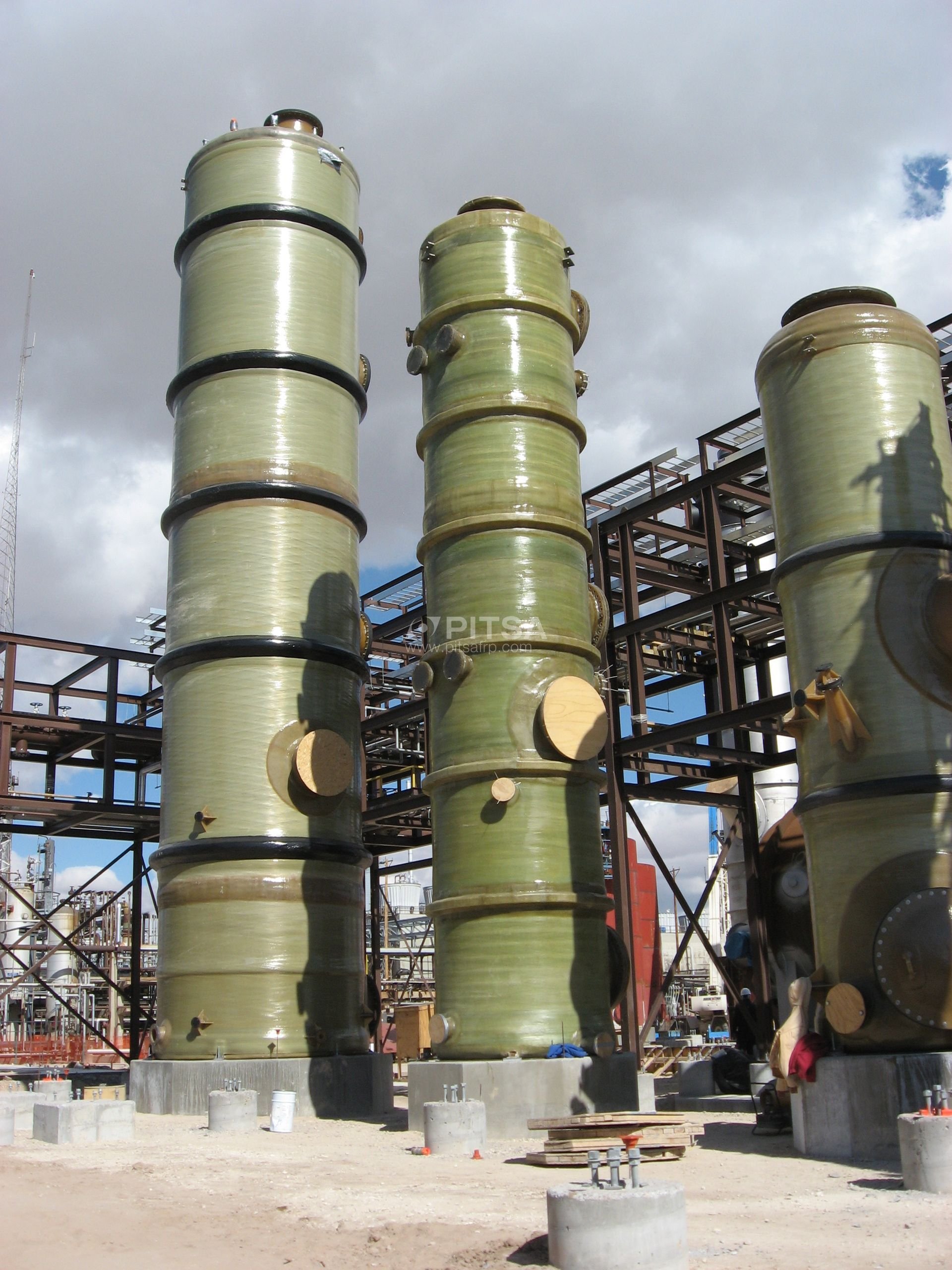 Three medium diameter FRP tanks being installed at a chemical processing facility.