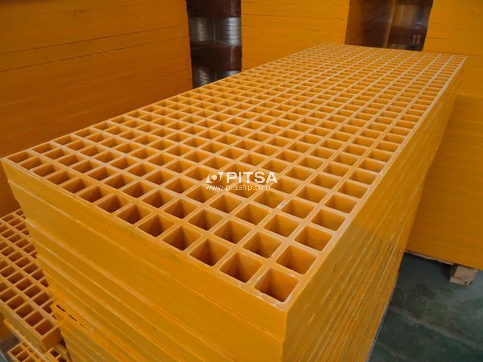 Stack of yellow FRP gratings suitable for corrosive environments.