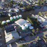 Aerial view of large green and white FRP tanks at PITSA's waterfront facility, ready for maritime transport, surrounded by industrial buildings.
