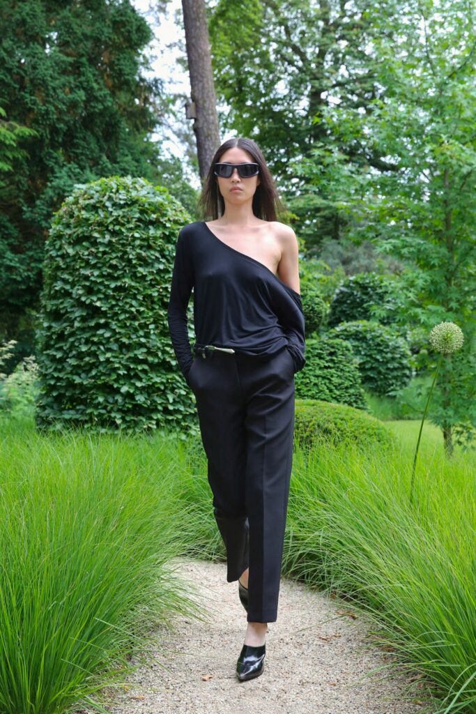 A relaxed black long-sleeve asymmetric top paired with tailored black pants.