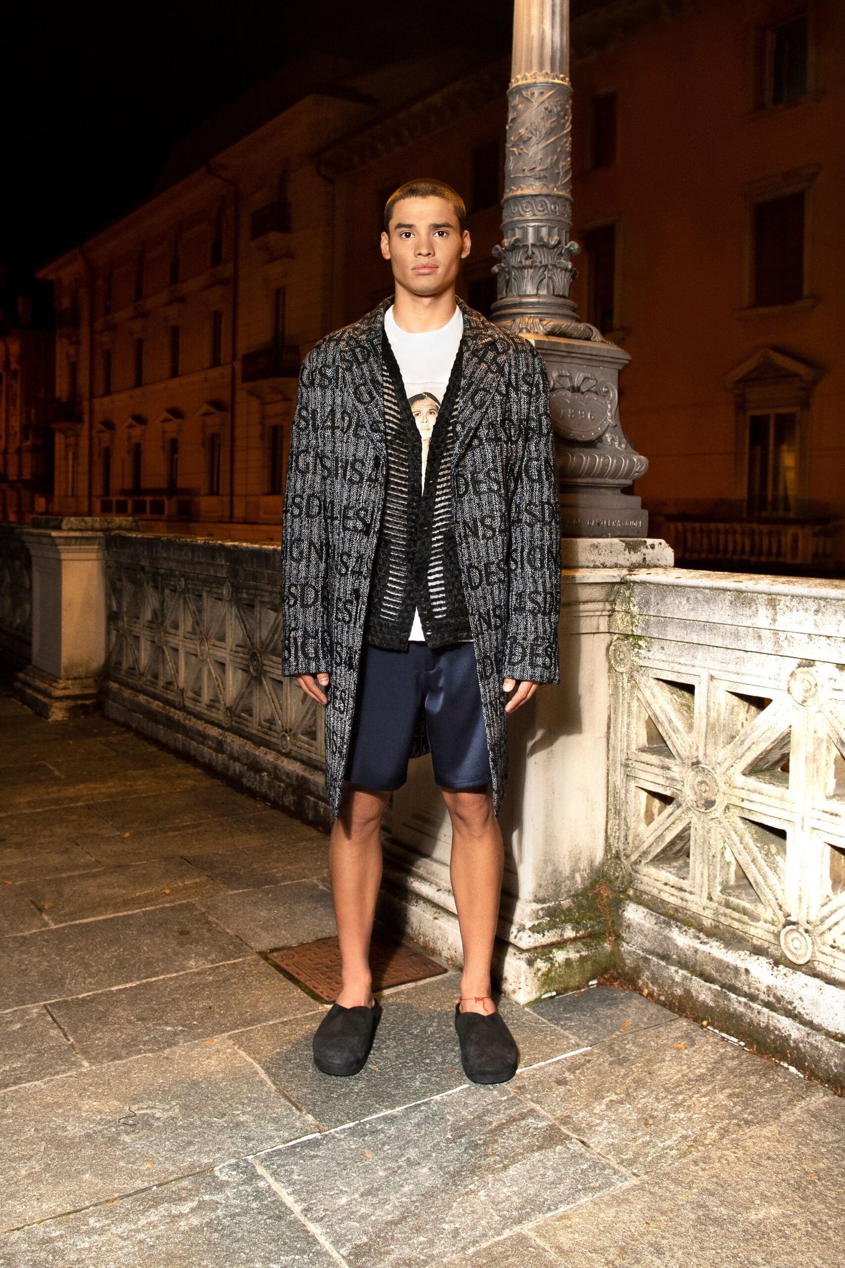 A relaxed-fit black and gray printed coat paired with casual shorts.