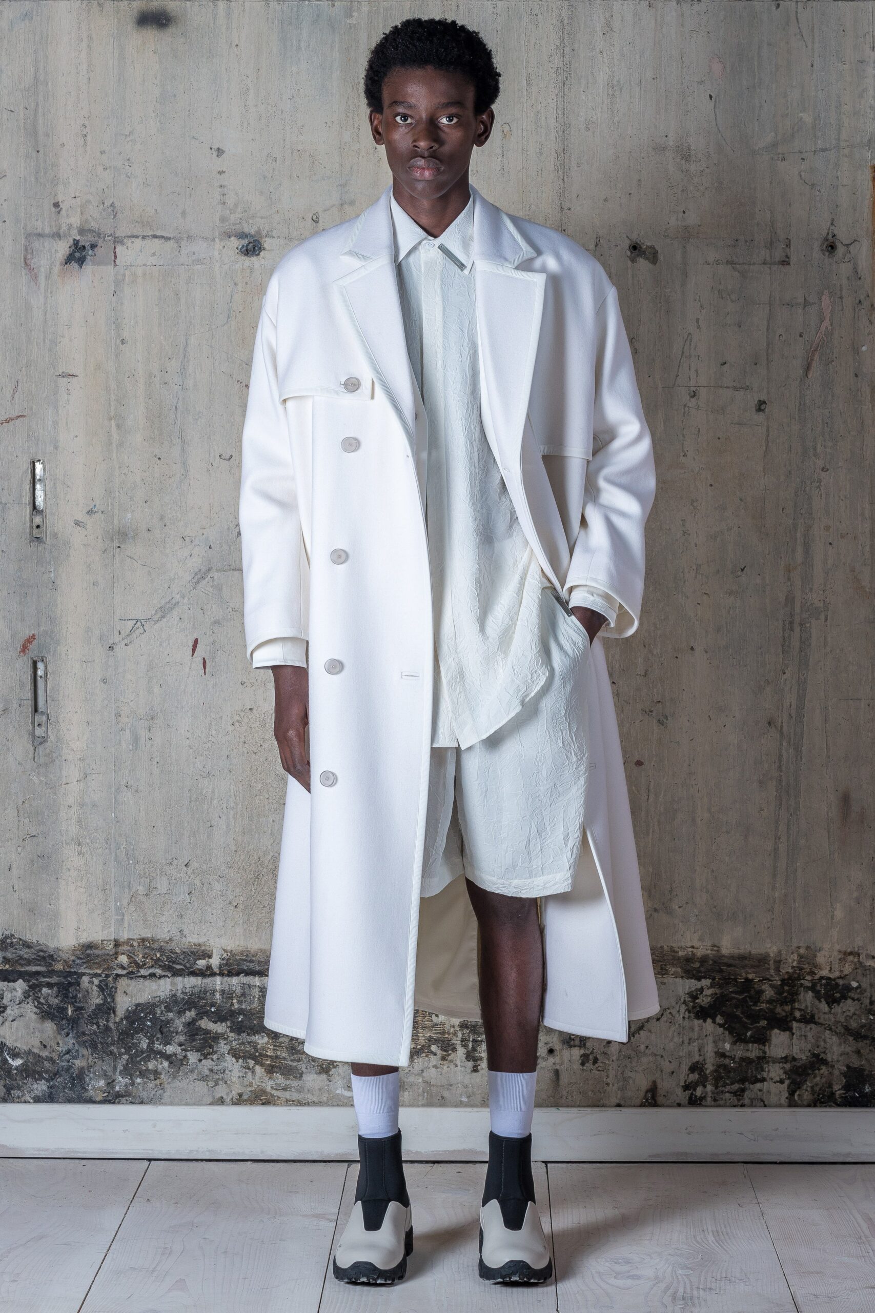 A relaxed white coat paired with collared long-sleeve shirt and shorts.