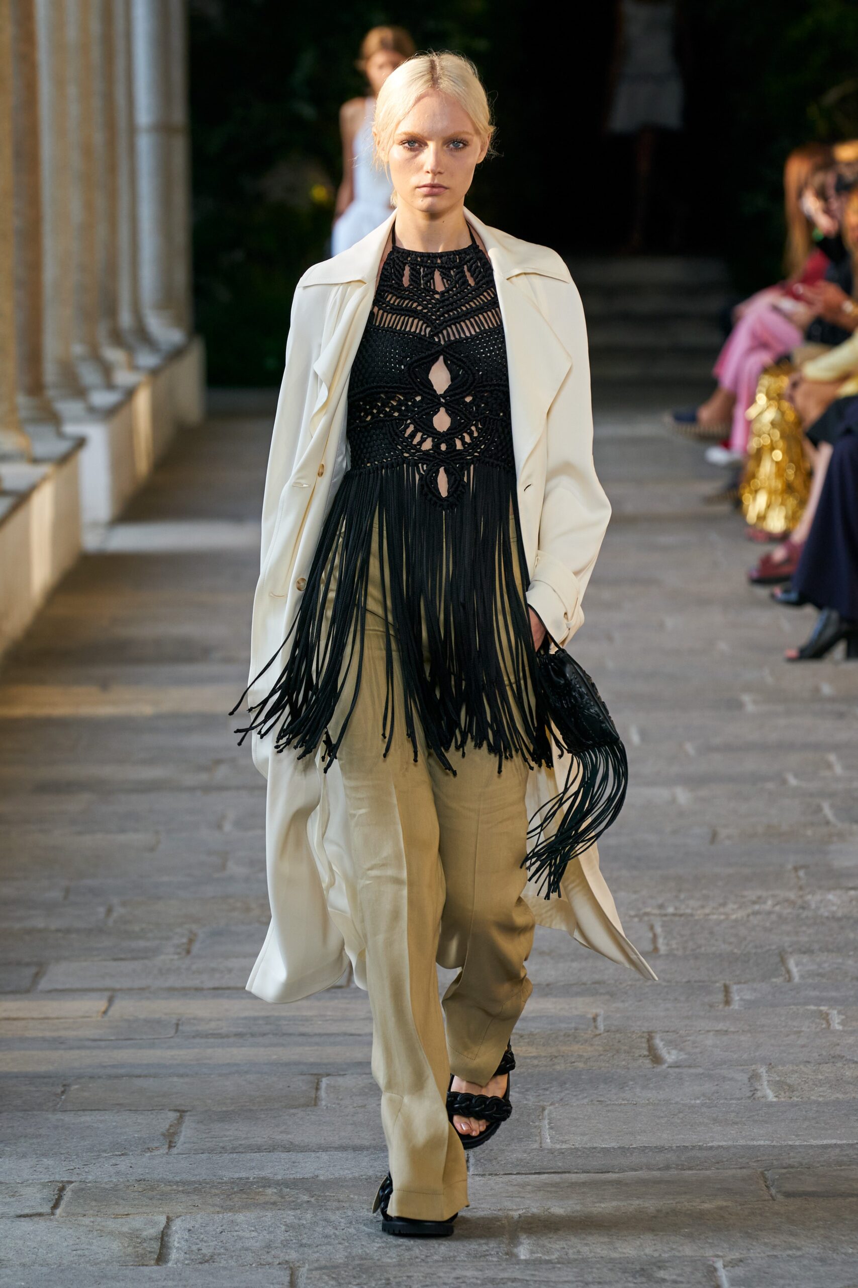white coat black fringed top beige pants