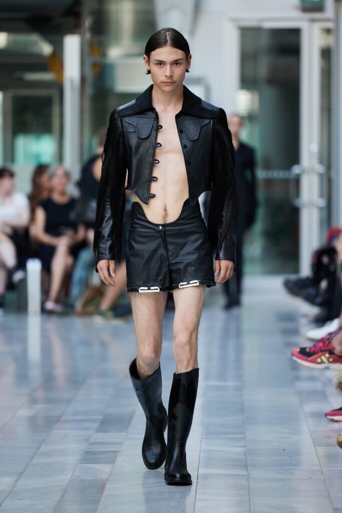 A fitted black leather jacket with a cutout design paired with a matching skirt.