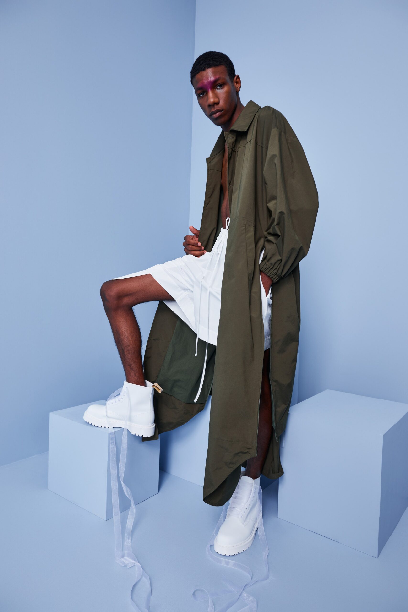This relaxed coat features a long-sleeve design with a collared neckline, presenting an asymmetric silhouette that flows effortlessly. Paired with crisp white shorts, the ensemble balances structure and ease, creating a modern, laid-back aesthetic.