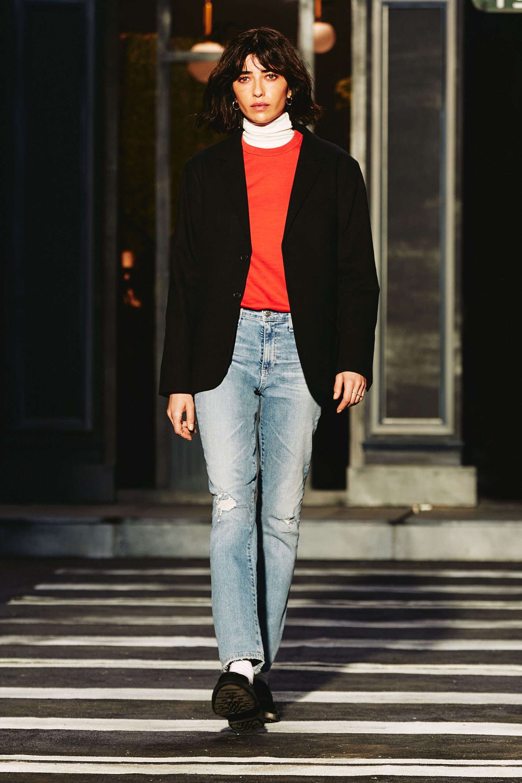 A fitted black blazer paired with a red t-shirt, featuring a collared neckline and buttoned detail.