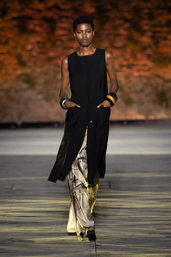 A relaxed black sleeveless dress with a collared design and asymmetric detail.