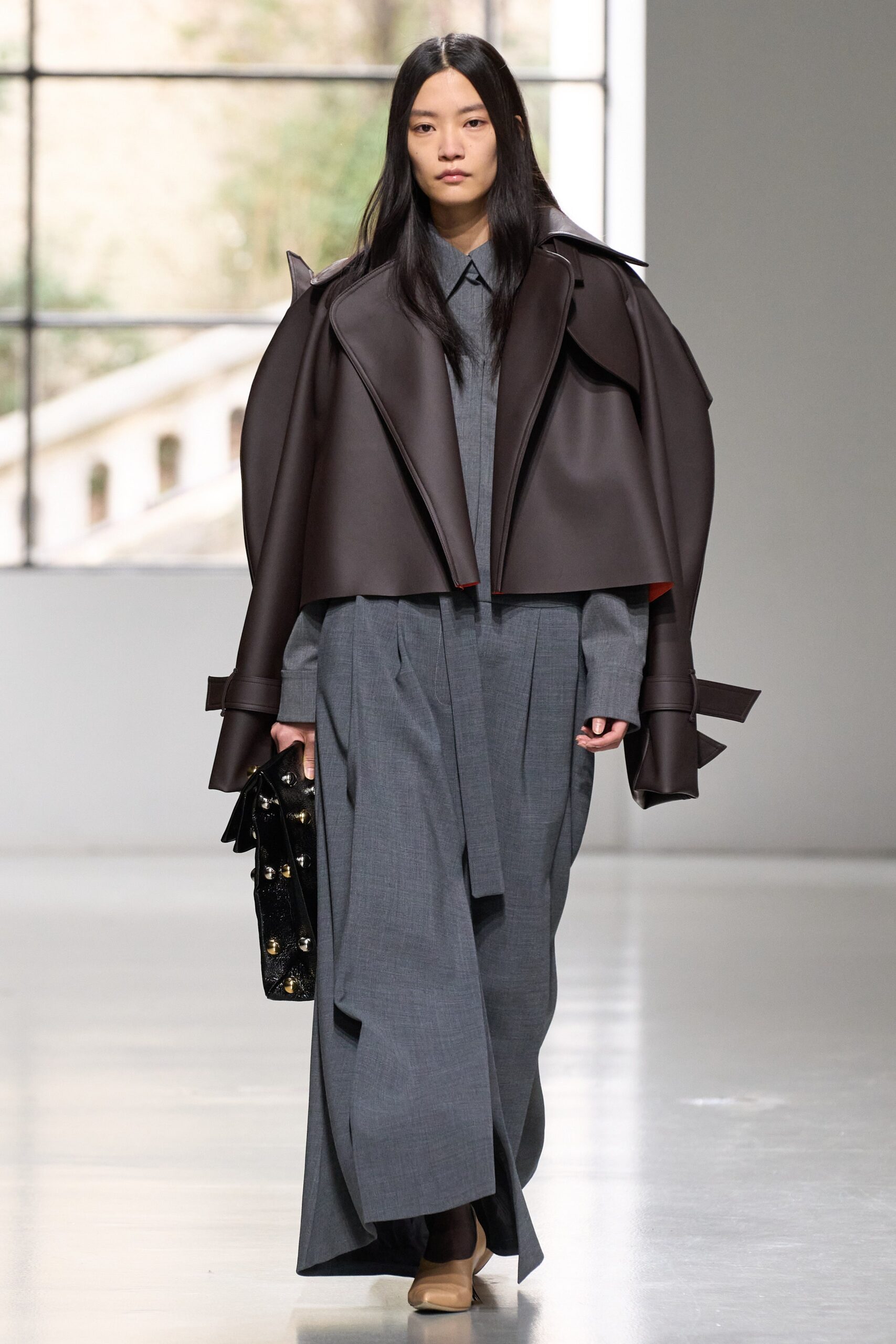 A relaxed gray coat layered over a pleated dress with an asymmetric design.