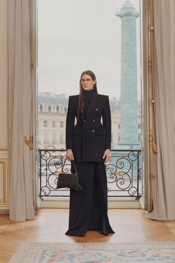 A tailored black wool suit with long sleeves and an asymmetric design.
