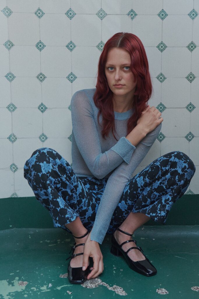A fitted long-sleeve blue top paired with black printed pants for a stylish look.