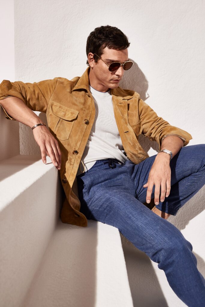 A relaxed brown suede jacket with a collared neckline paired with blue cotton pants.