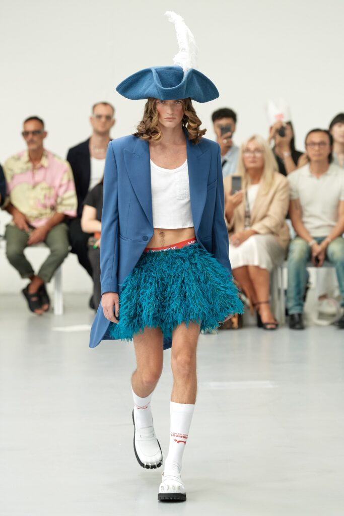 A relaxed blue jacket paired with a fringed teal skirt, featuring a long-sleeve and collared design.