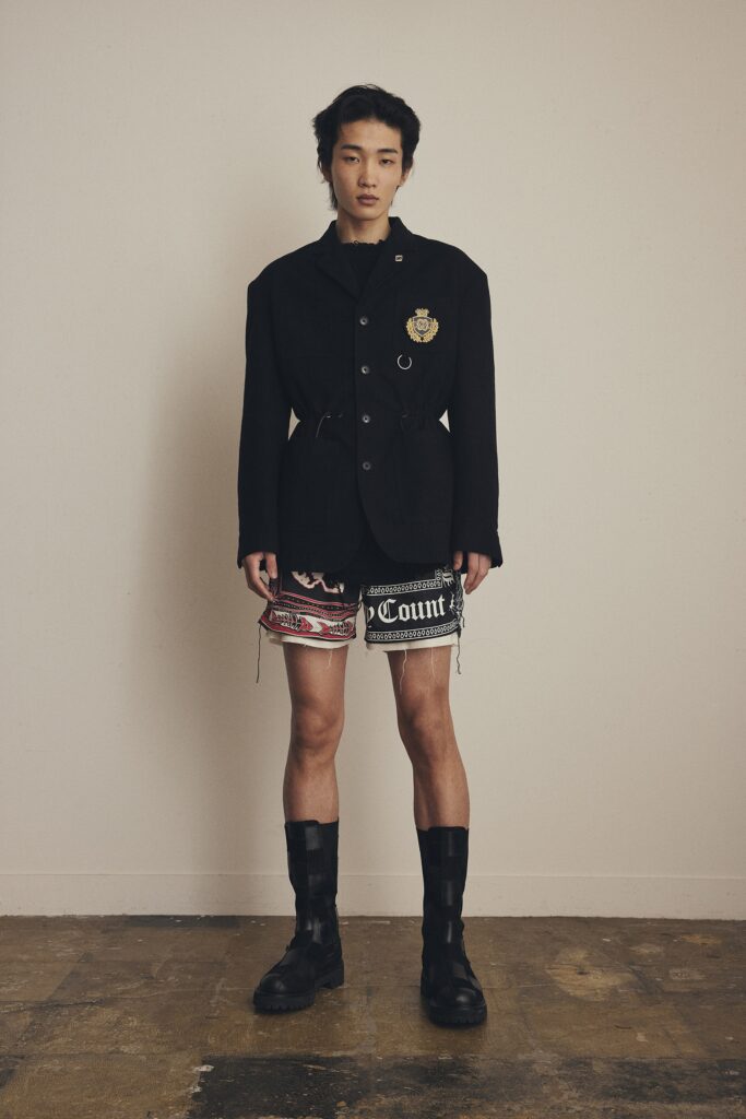 A fitted black jacket with long sleeves and a collared design paired with stylish shorts.