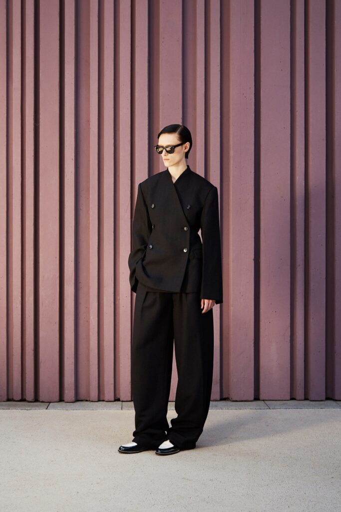 An oversized black wool blazer with long sleeves and wide-leg pants, featuring a collared design.