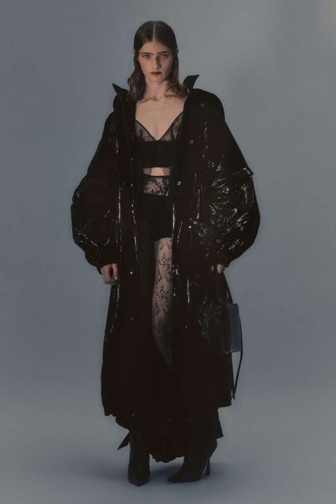 An oversized black leather coat with a V-neckline and layered design.