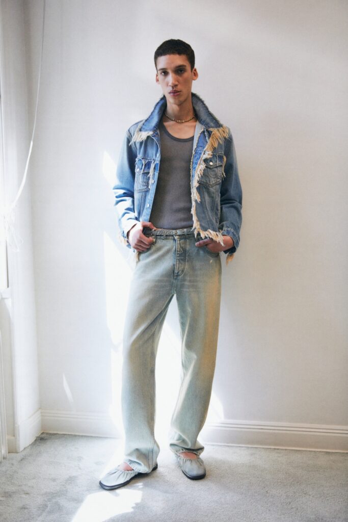 A relaxed blue denim jacket with fringed details paired with wide-leg gray cotton pants.