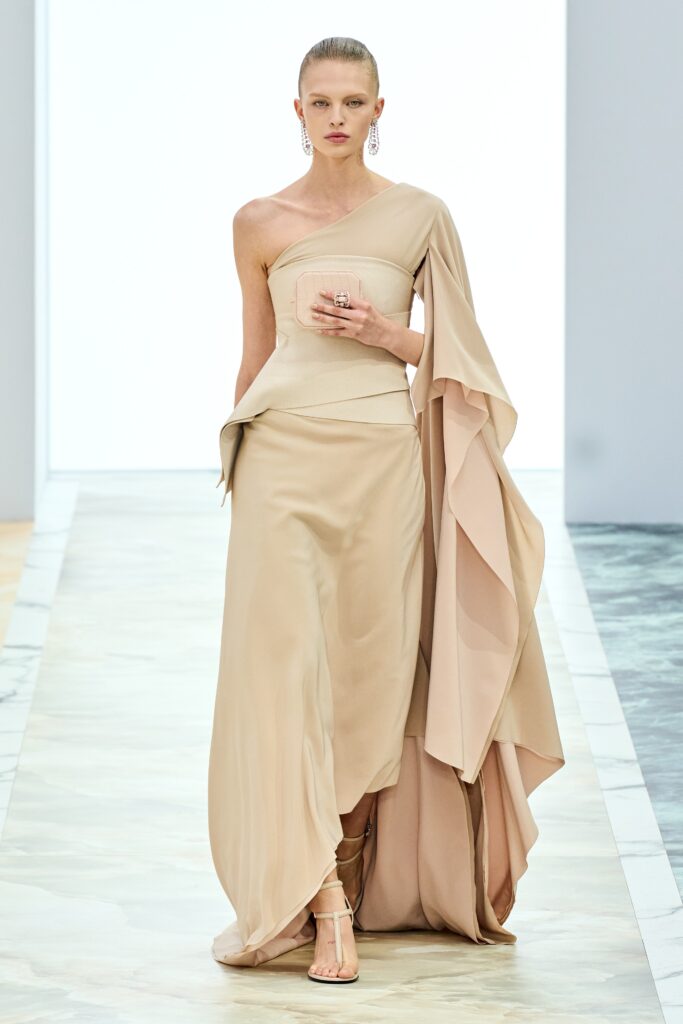 A fitted beige silk dress with a sleeveless design and asymmetric detailing.