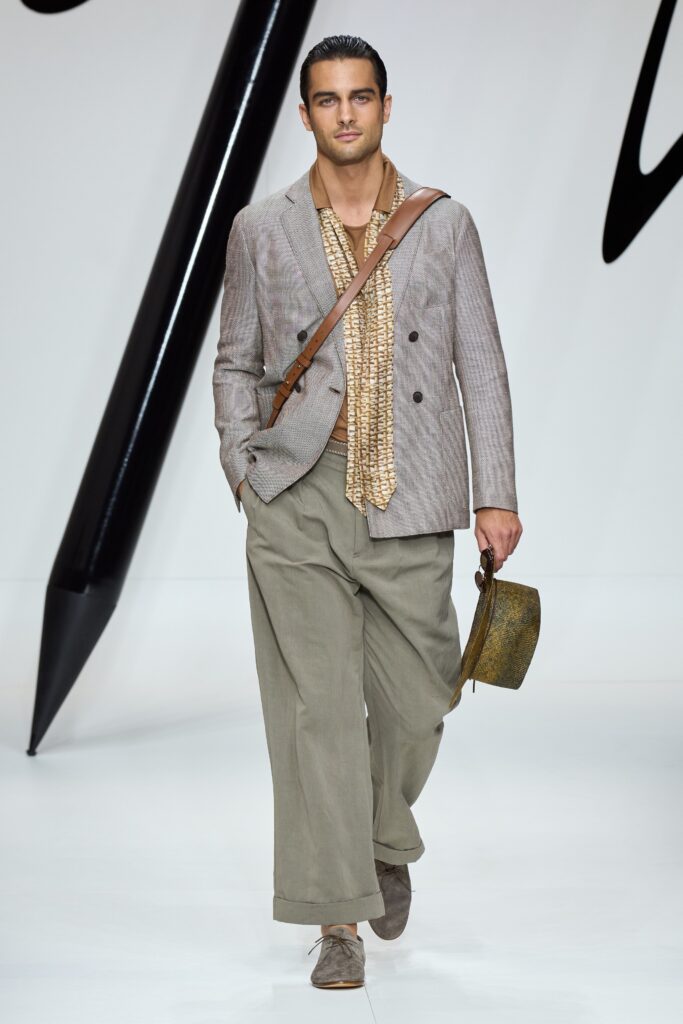 A relaxed-fit beige cotton blazer with long sleeves and collared design paired with wide-leg gray pants.