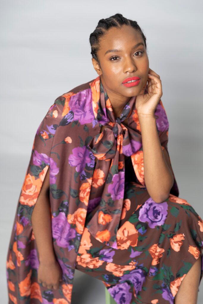 A relaxed floral brown silk dress paired with a matching cape featuring vibrant colors.