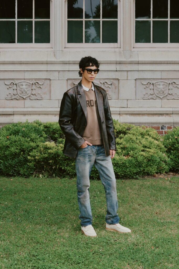 A relaxed black leather jacket layered over a brown collared shirt.