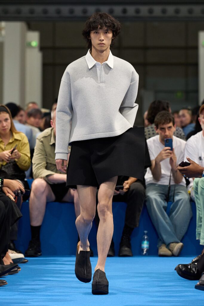 A relaxed gray long-sleeve collared top paired with an asymmetric black skirt.