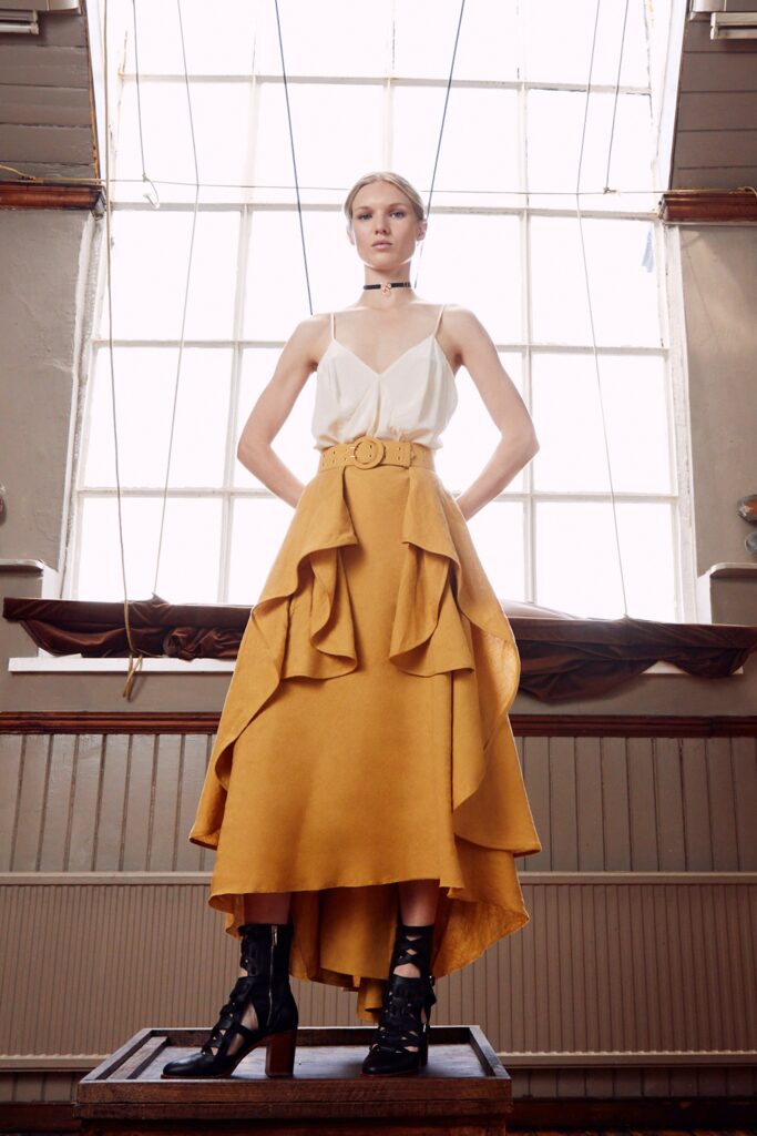 A fitted white sleeveless top paired with a tiered yellow skirt, creating a stylish ensemble.