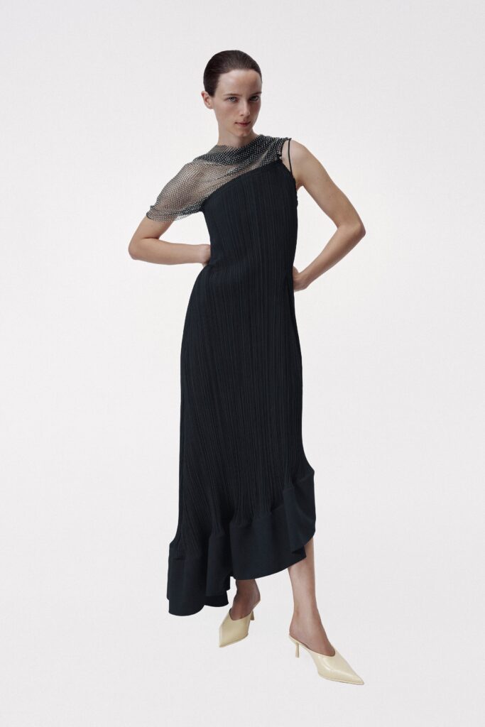 A fitted black silk dress with a sleeveless design and pleated asymmetric detailing.