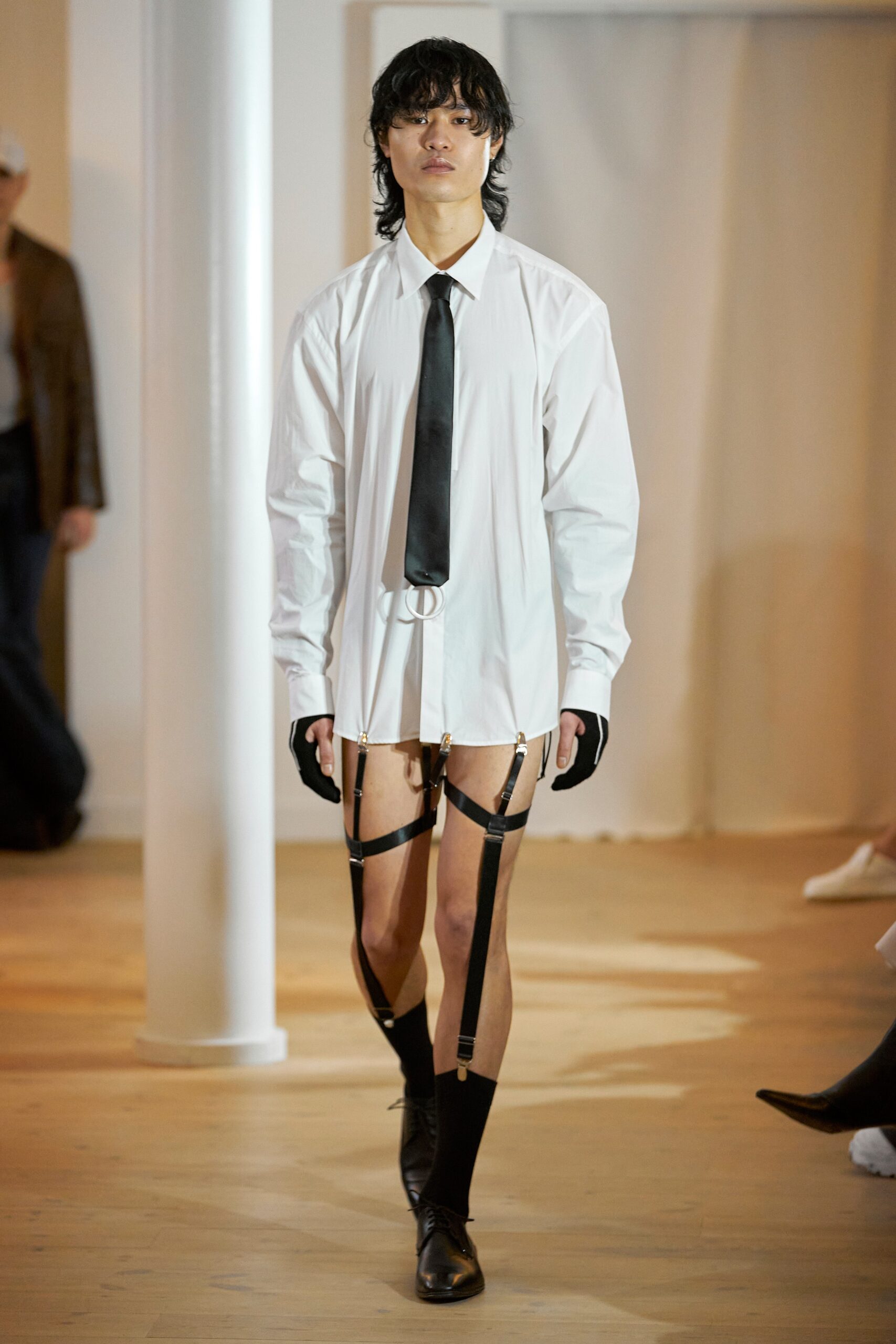A fitted white long-sleeve collared shirt paired with black pants featuring an asymmetric design.