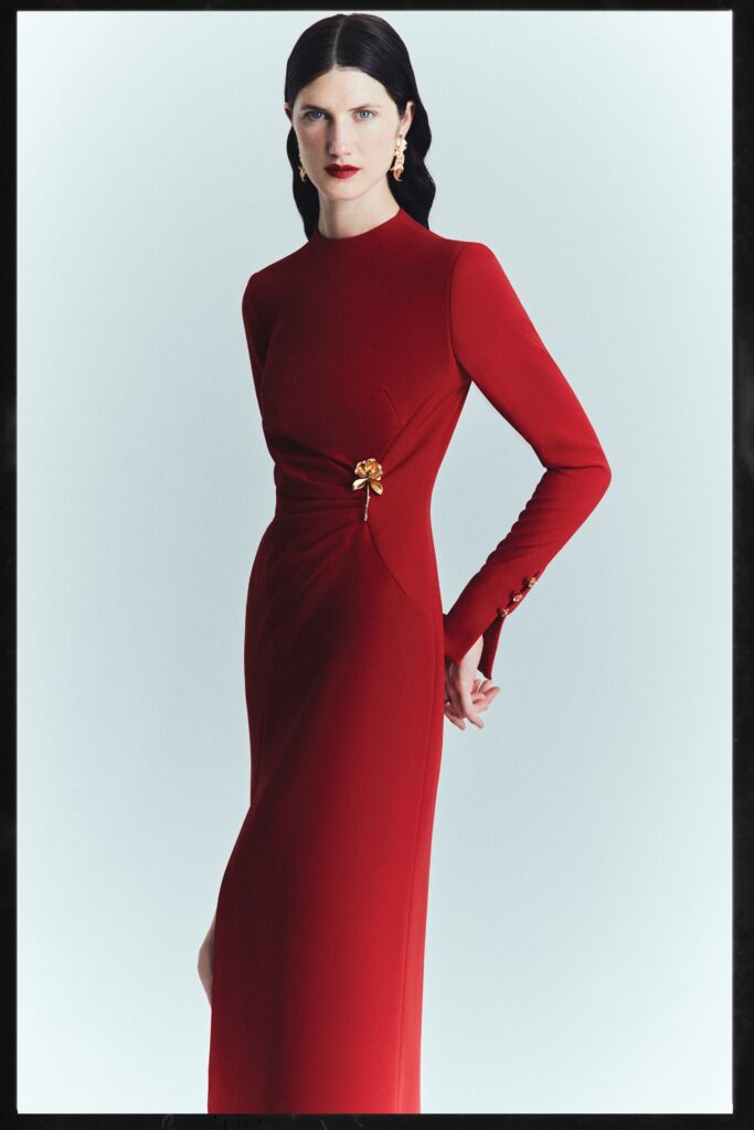 A fitted red silk dress with long sleeves, a high neckline, and an asymmetric design detail.