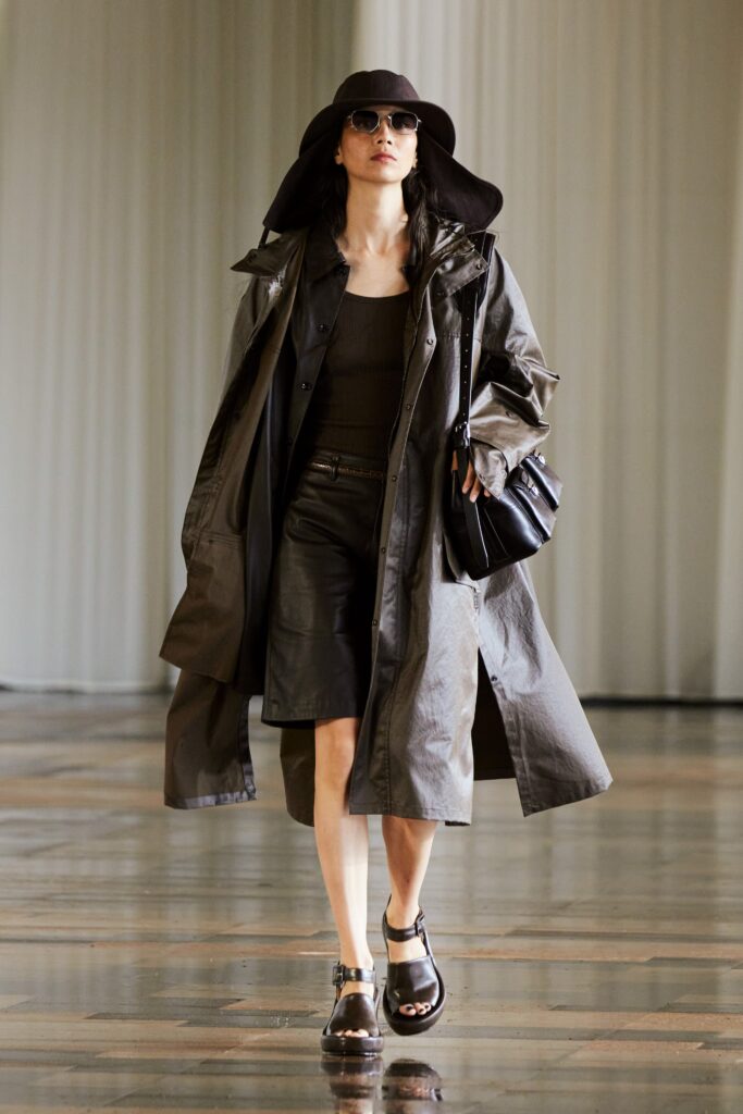 A fitted black leather coat layered over a sleeveless top and a matching skirt.