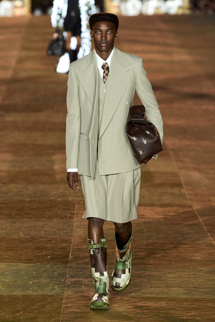 A tailored beige suit featuring a collared long-sleeve jacket and an asymmetric skirt.