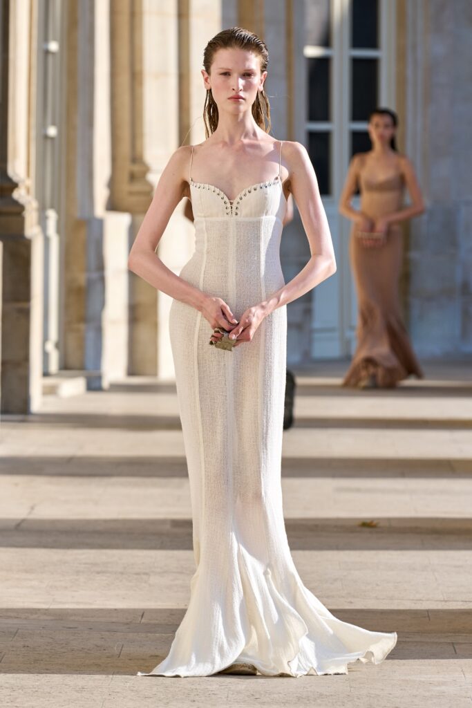 A fitted white silk dress with a V-neckline and flared silhouette.