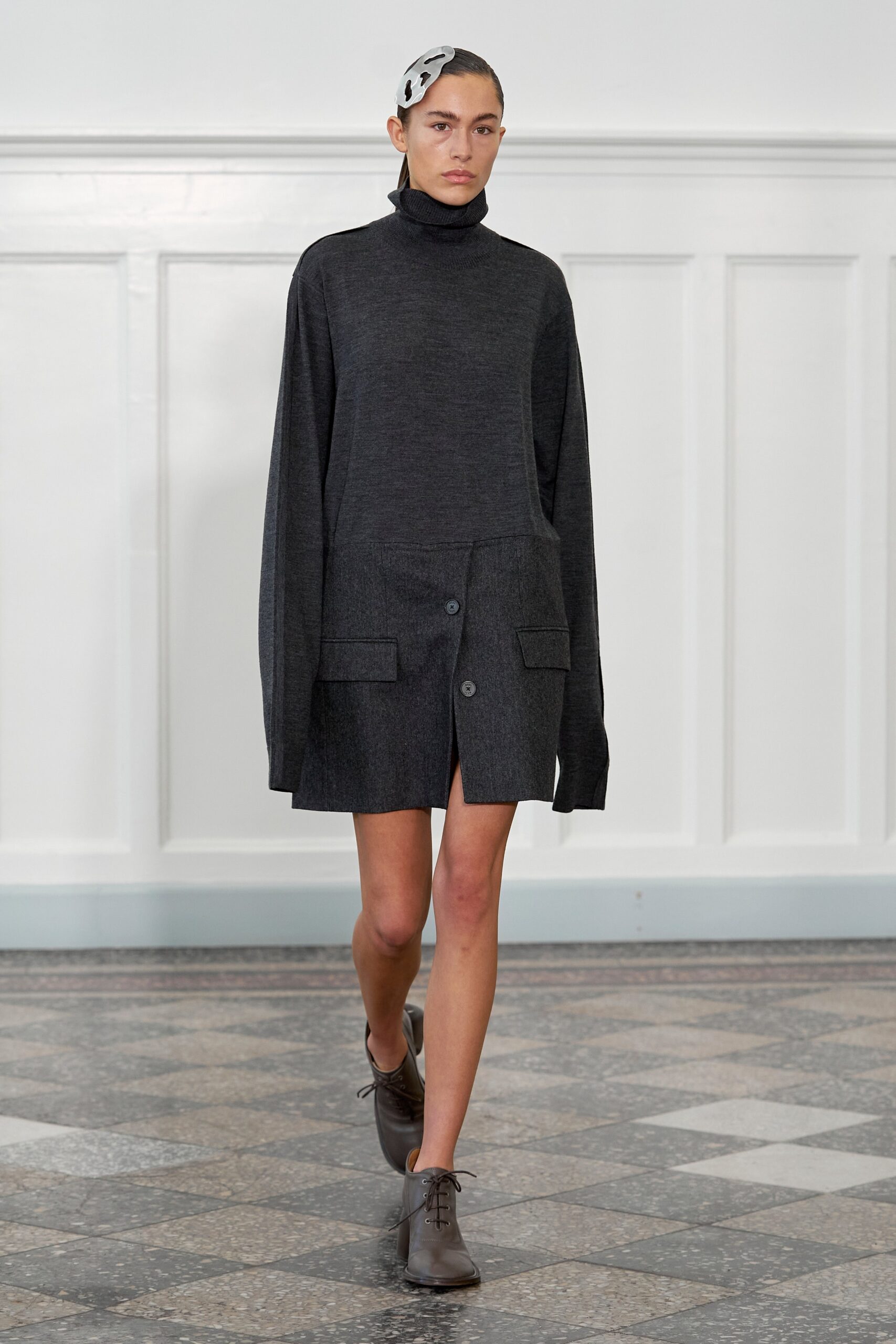 A relaxed gray wool dress with a turtleneck and buttoned asymmetric design.