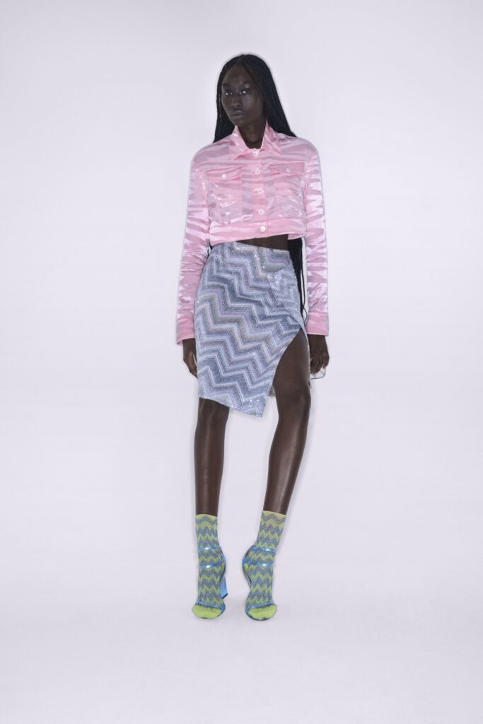 A fitted pink silk long-sleeve top with a collared design paired with an asymmetric blue skirt.