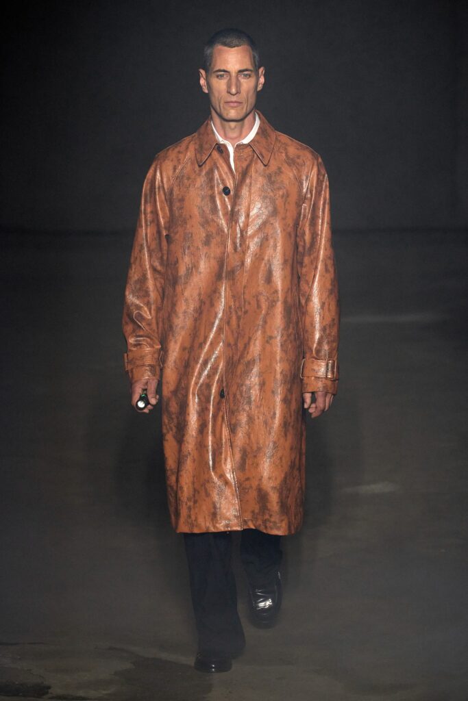 A relaxed brown leather coat with long sleeves and a collared design, featuring button details.