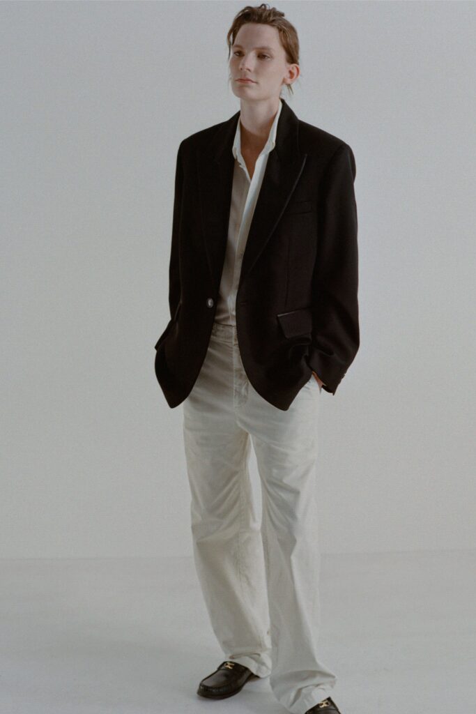 A relaxed black blazer paired with white straight-leg pants and a collared shirt.