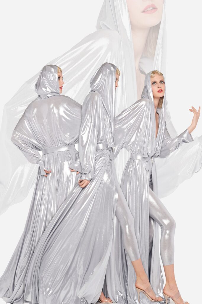 A relaxed silver metallic dress with a hood and long sleeves, featuring a draped design.