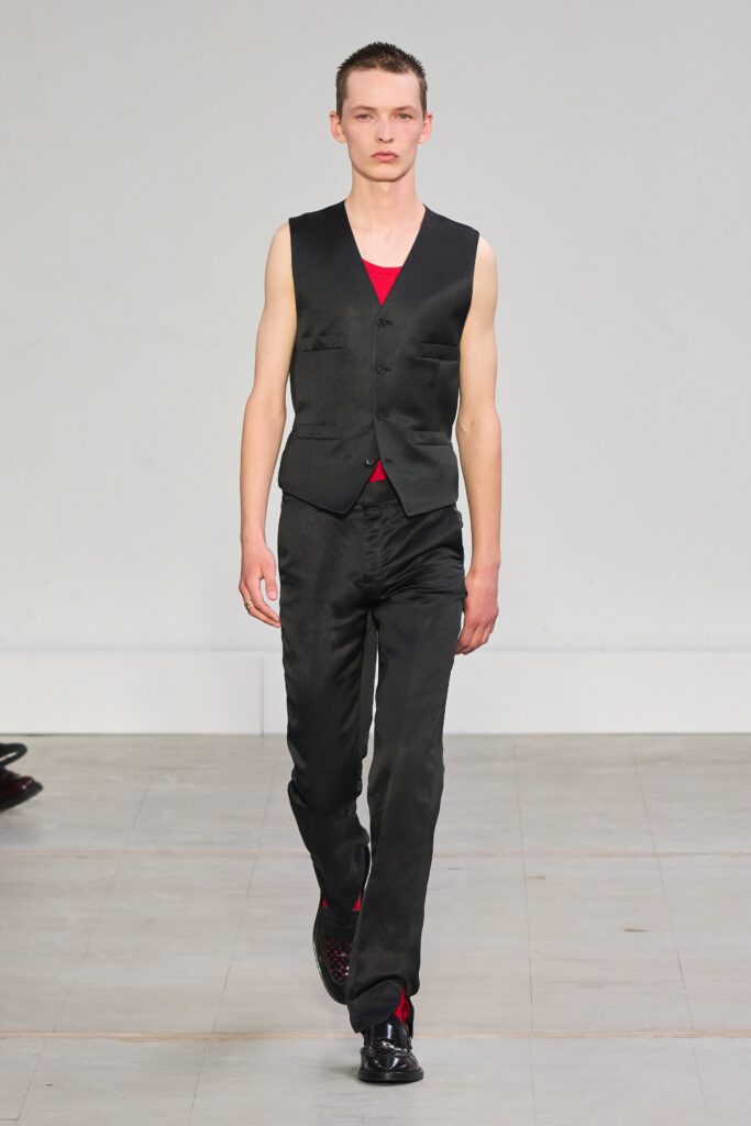 A fitted black silk vest paired with straight-leg pants, featuring a sleeveless design and V-neckline.