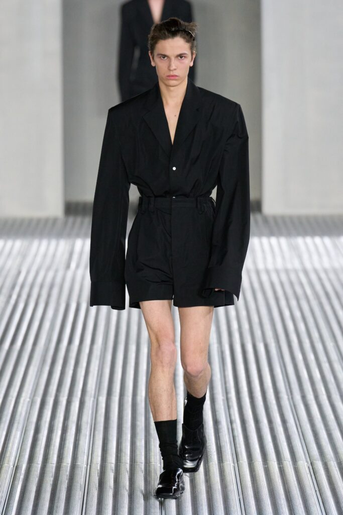 An oversized black jacket with long sleeves and a collared design paired with matching shorts.