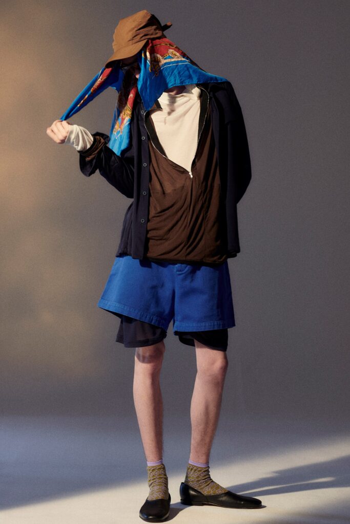 A relaxed brown cotton long-sleeve shirt layered over blue shorts.