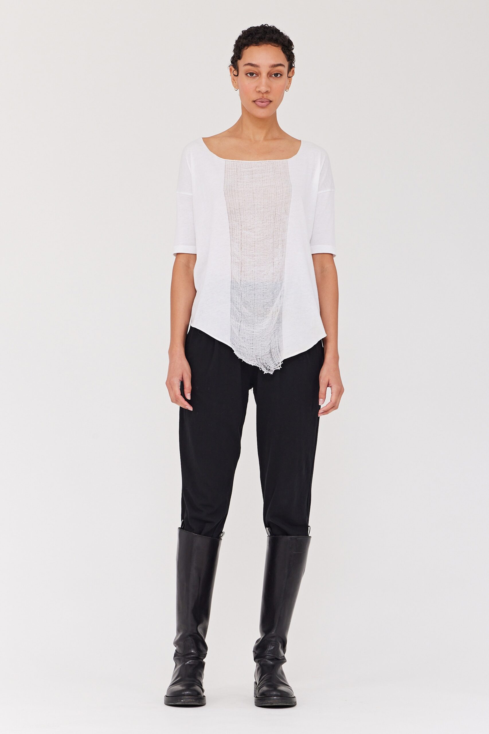 A fitted white top with short sleeves and asymmetric design paired with black fitted pants.