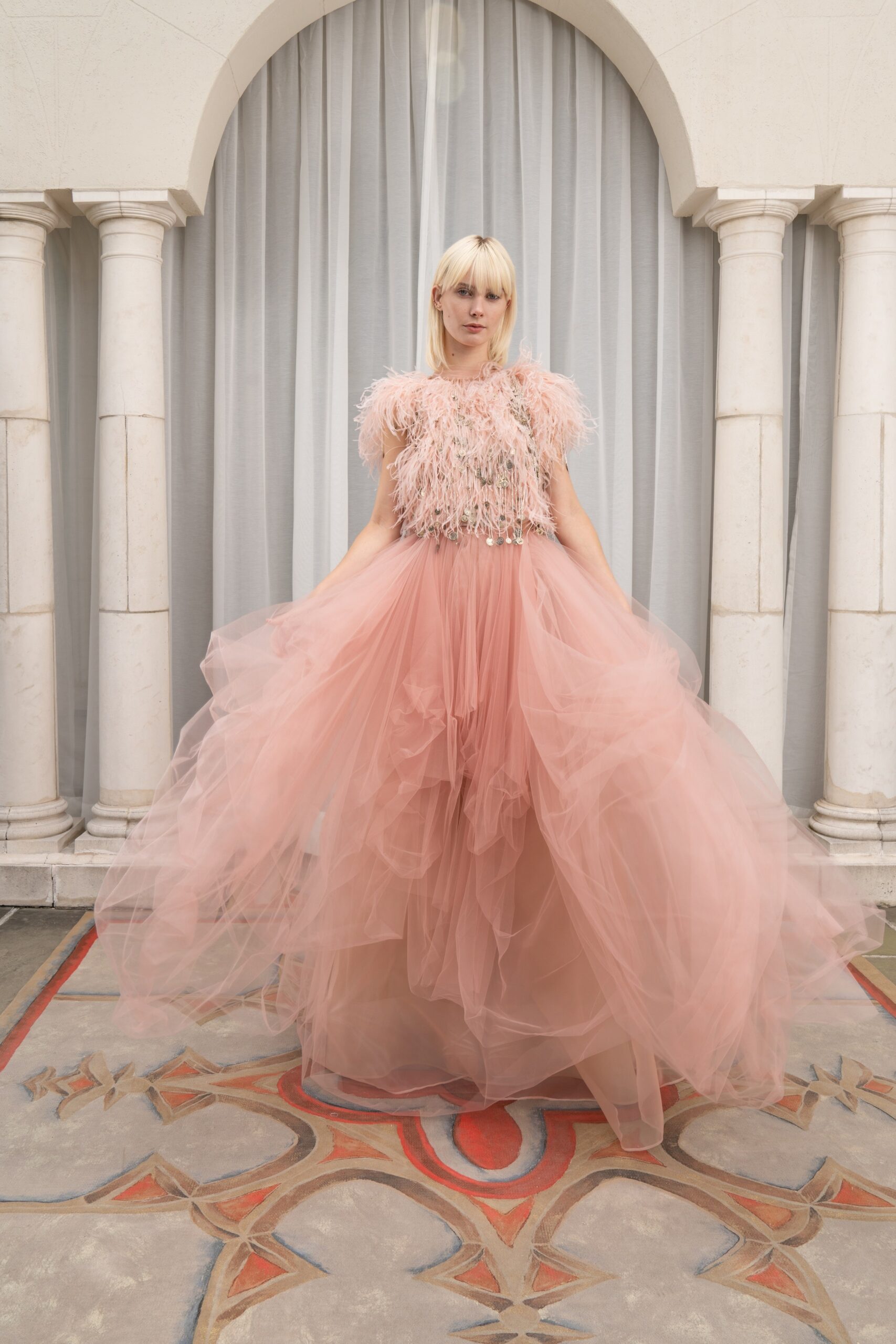 A relaxed pink tulle sleeveless dress featuring a high neckline and tiered layers.