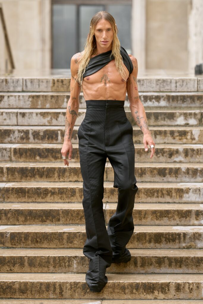 A fitted black sleeveless top with an asymmetric design paired with tailored black pants.