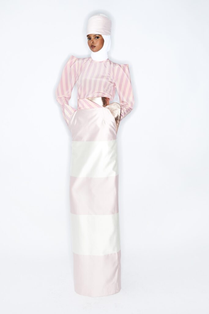 A fitted pink and white striped dress with long sleeves and a high neckline featuring a tiered design.