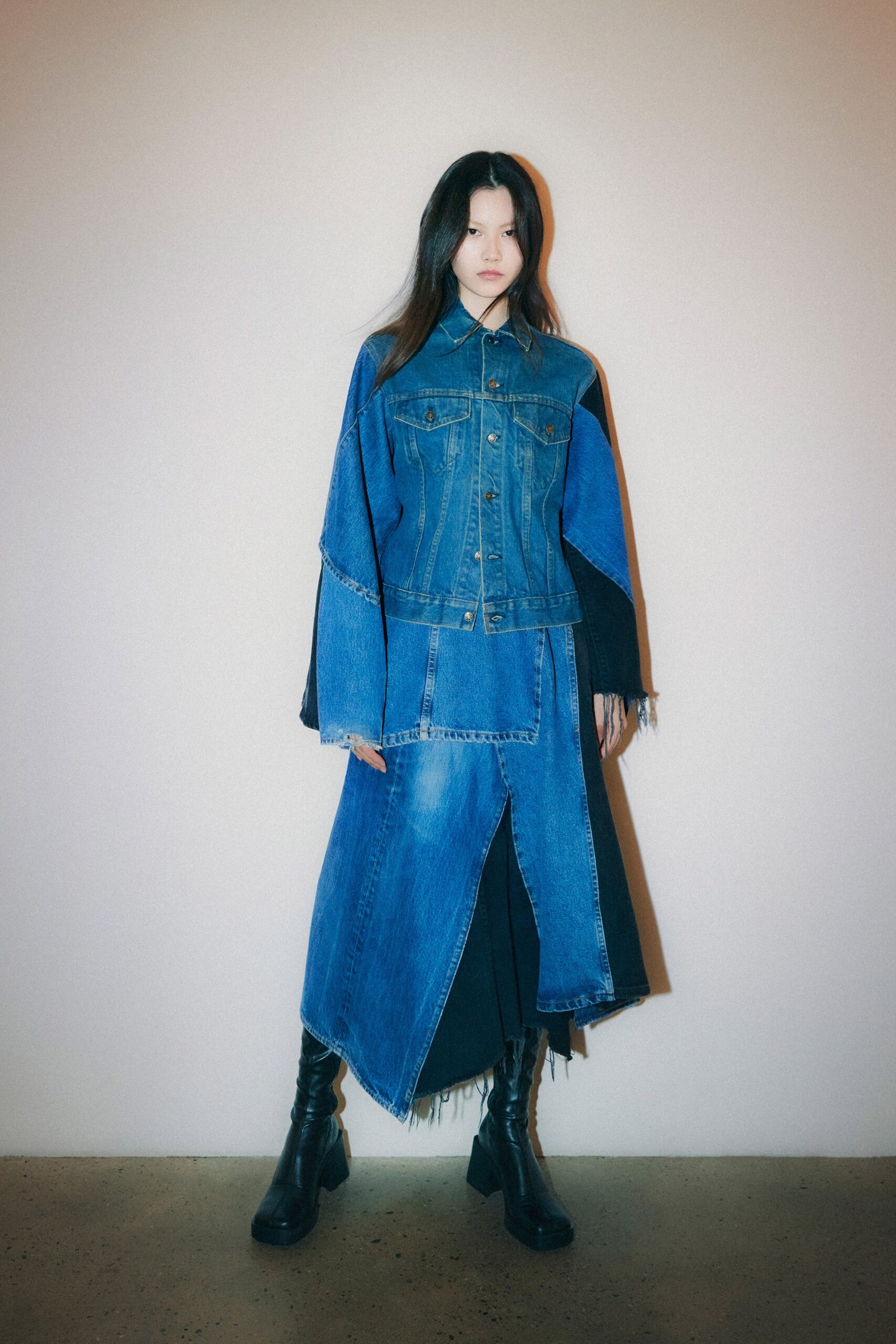 A relaxed blue denim dress with long sleeves, a collared neckline, and an asymmetric design.