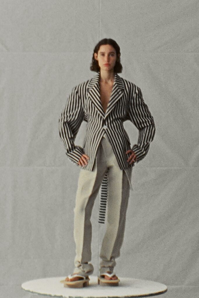 A fitted black and white striped jacket with long sleeves and a collared design.