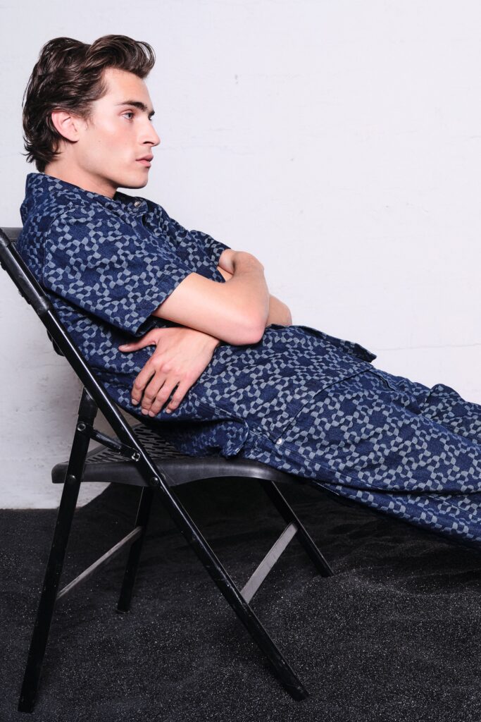 A relaxed blue cotton jumpsuit with short sleeves and a collared neckline featuring a unique print.