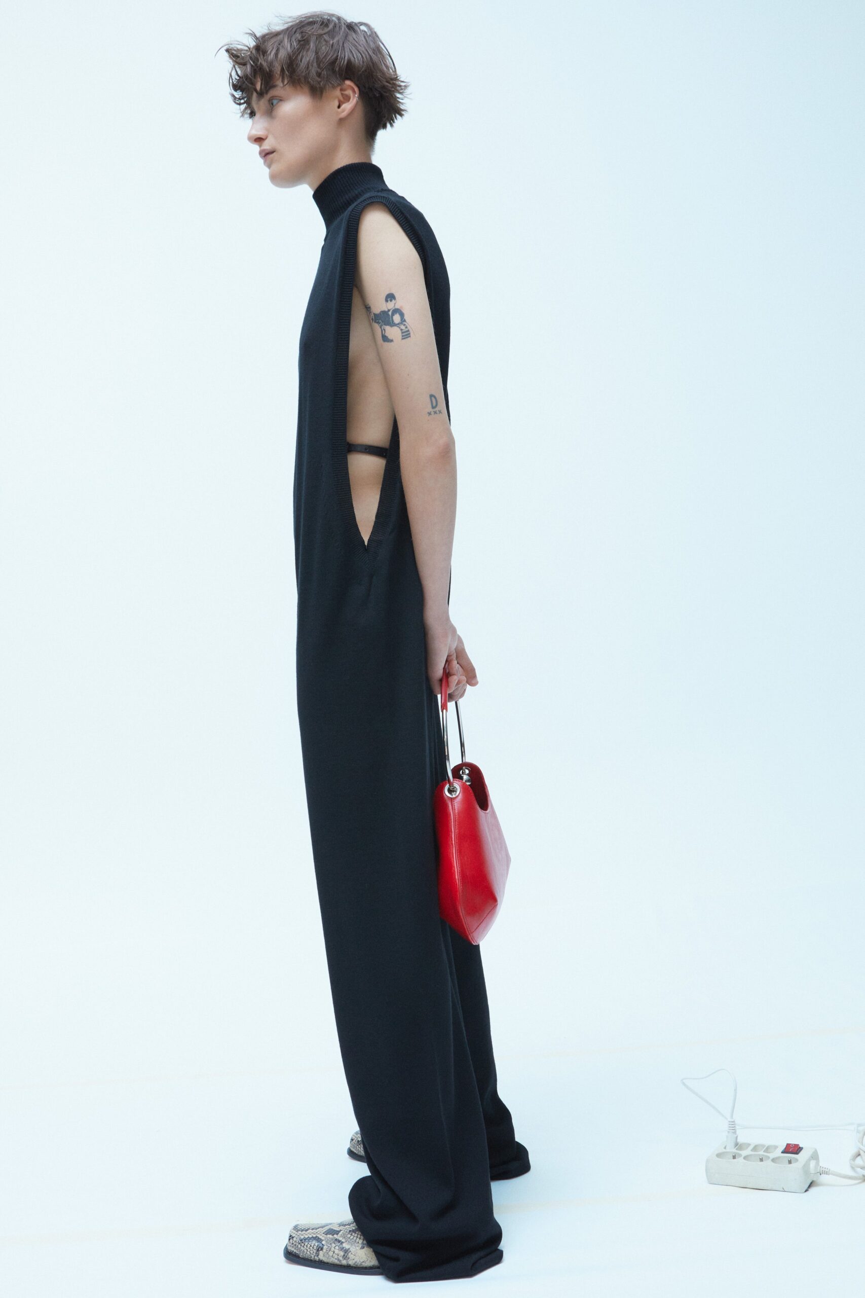 A relaxed black sleeveless jumpsuit with a high neckline and asymmetric design.