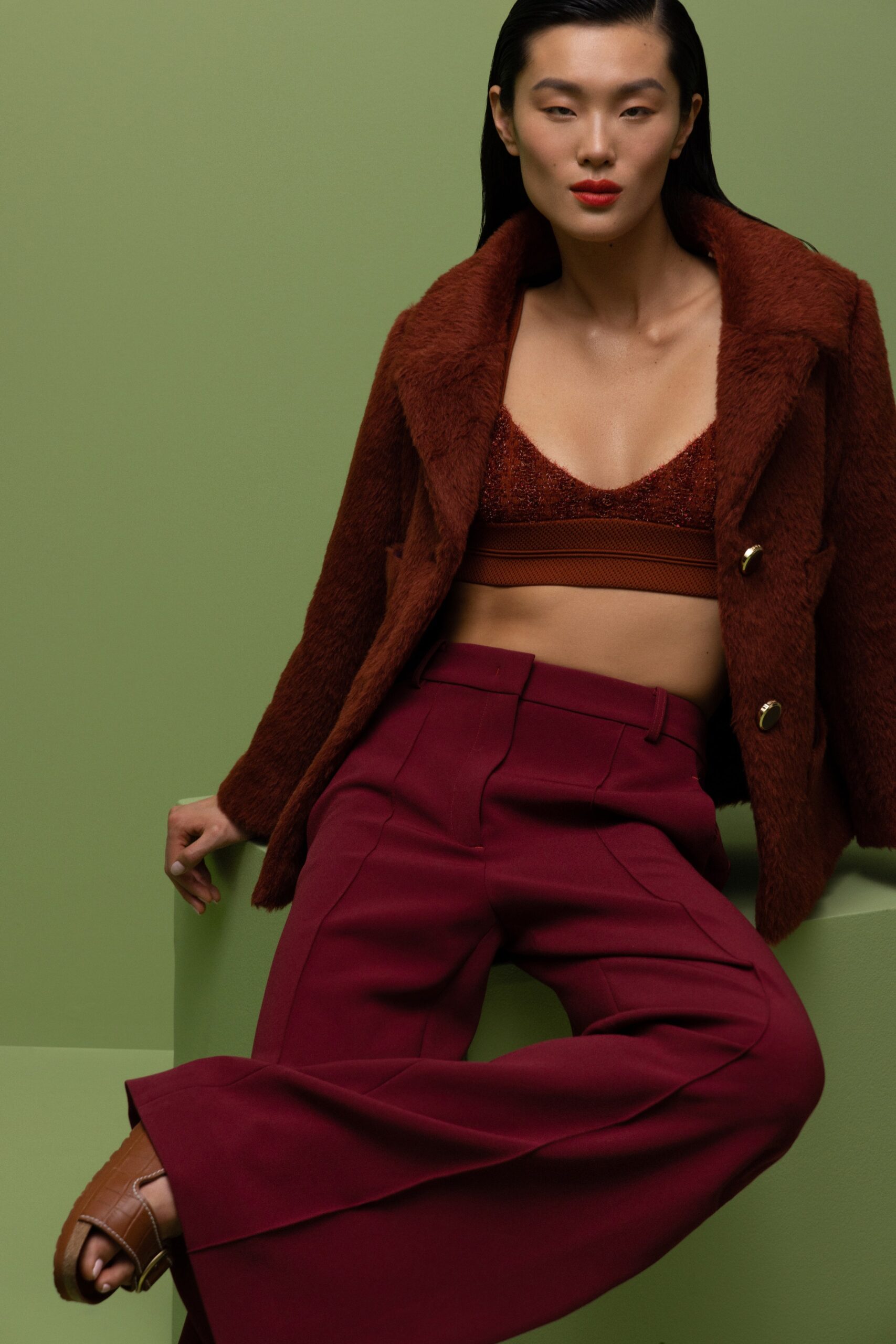 A fitted brown wool jacket with a collared design paired with flared burgundy pants.