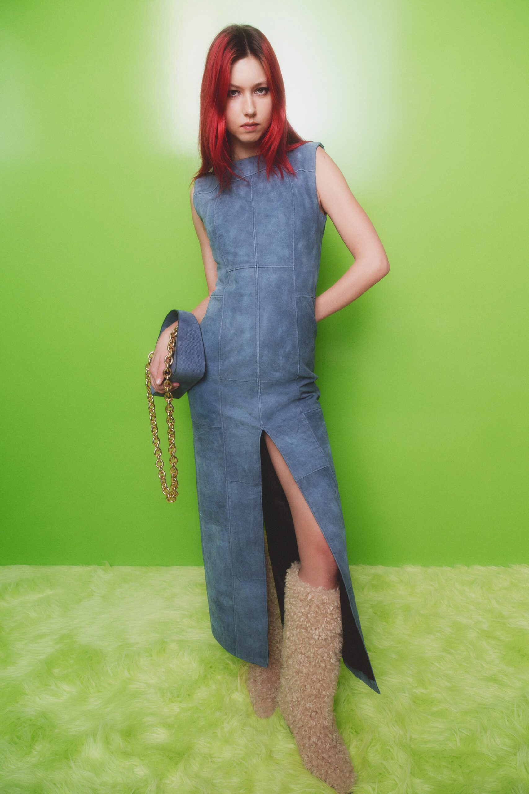 A fitted blue denim sleeveless dress with a high neckline and a side slit.